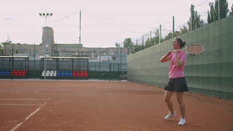 Slow-Motion-commercial-footage-of-tennis-practice-through-the-tennis-court-net.-Straight-view-of-a-female-athlete-playing-the-tennis-game.-A-teenage-sportsman-is-hitting-the-ball-during-sport-training